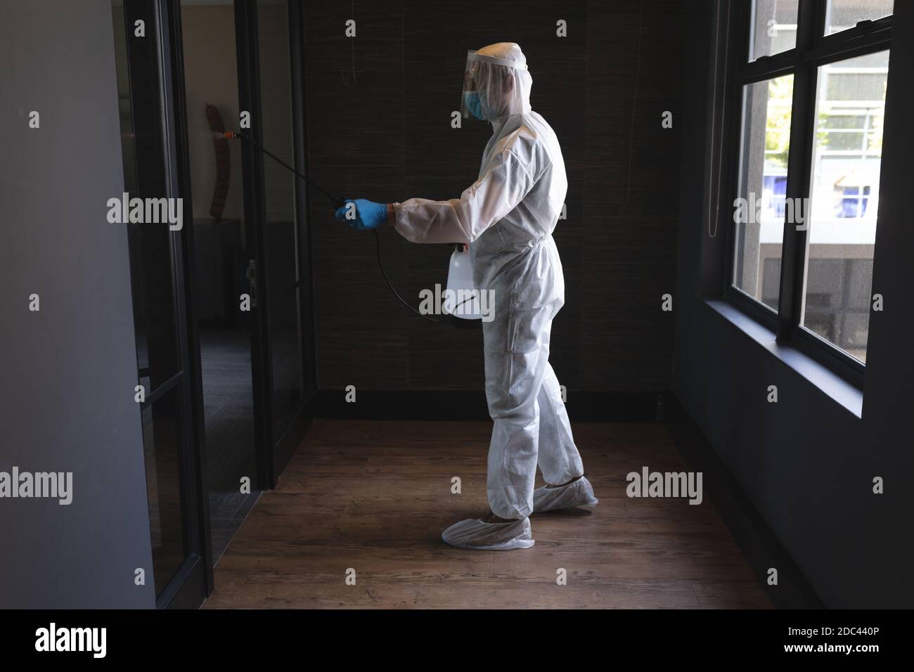 Health worker wearing protective clothes cleaning office using disinfectant Stock Photo