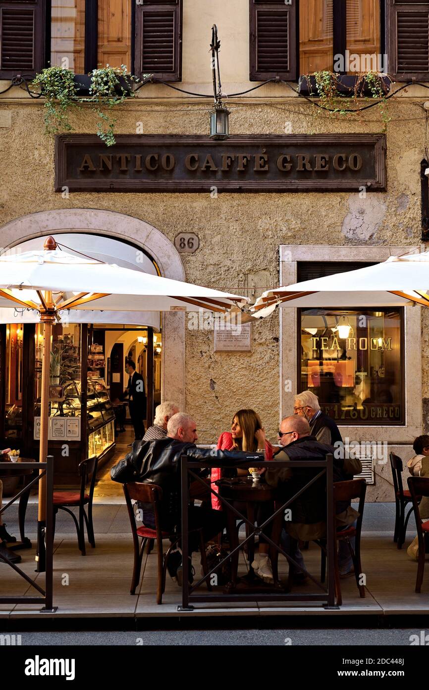 Famous historical Antico Caffè Greco. People talk, sitting at tables outside. The tables are exceptionally out due to Covid 19. Rome, Italy, EU. Stock Photo