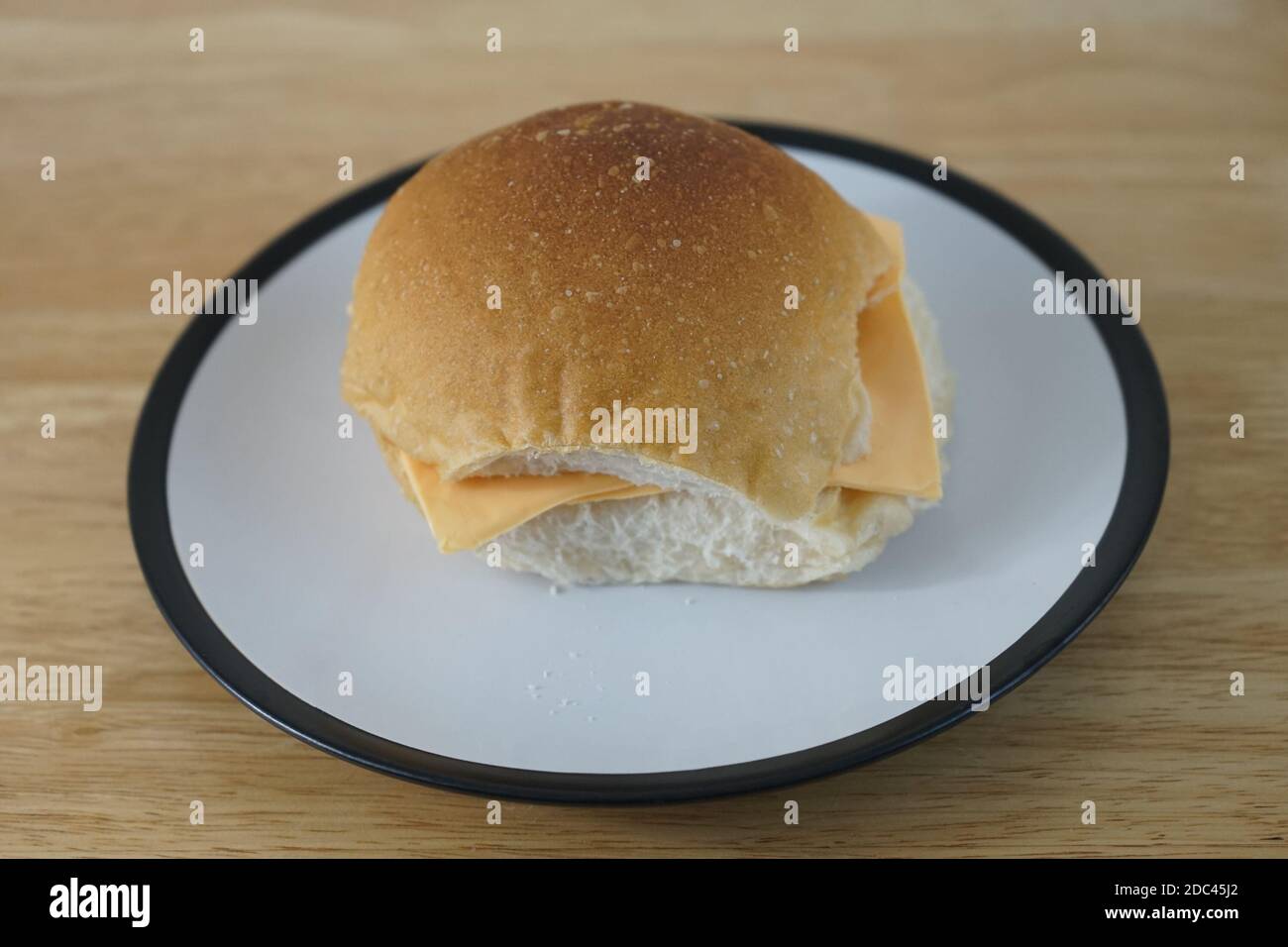 Lonely looking plain cheese roll on a plate Stock Photo
