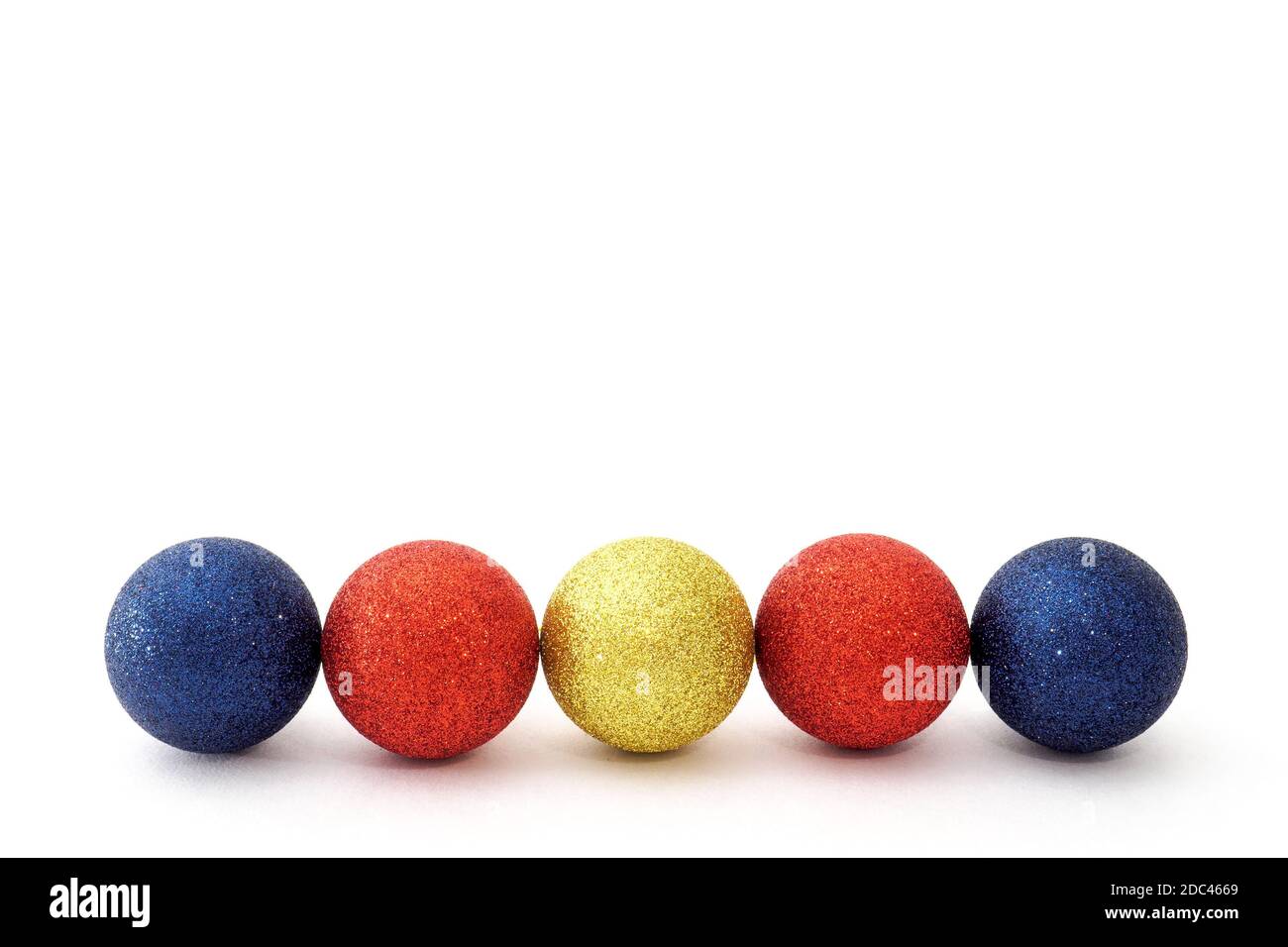 Five Christmas baubles blue, red and yellow color in row on a white background. Selective focus, copy space Stock Photo
