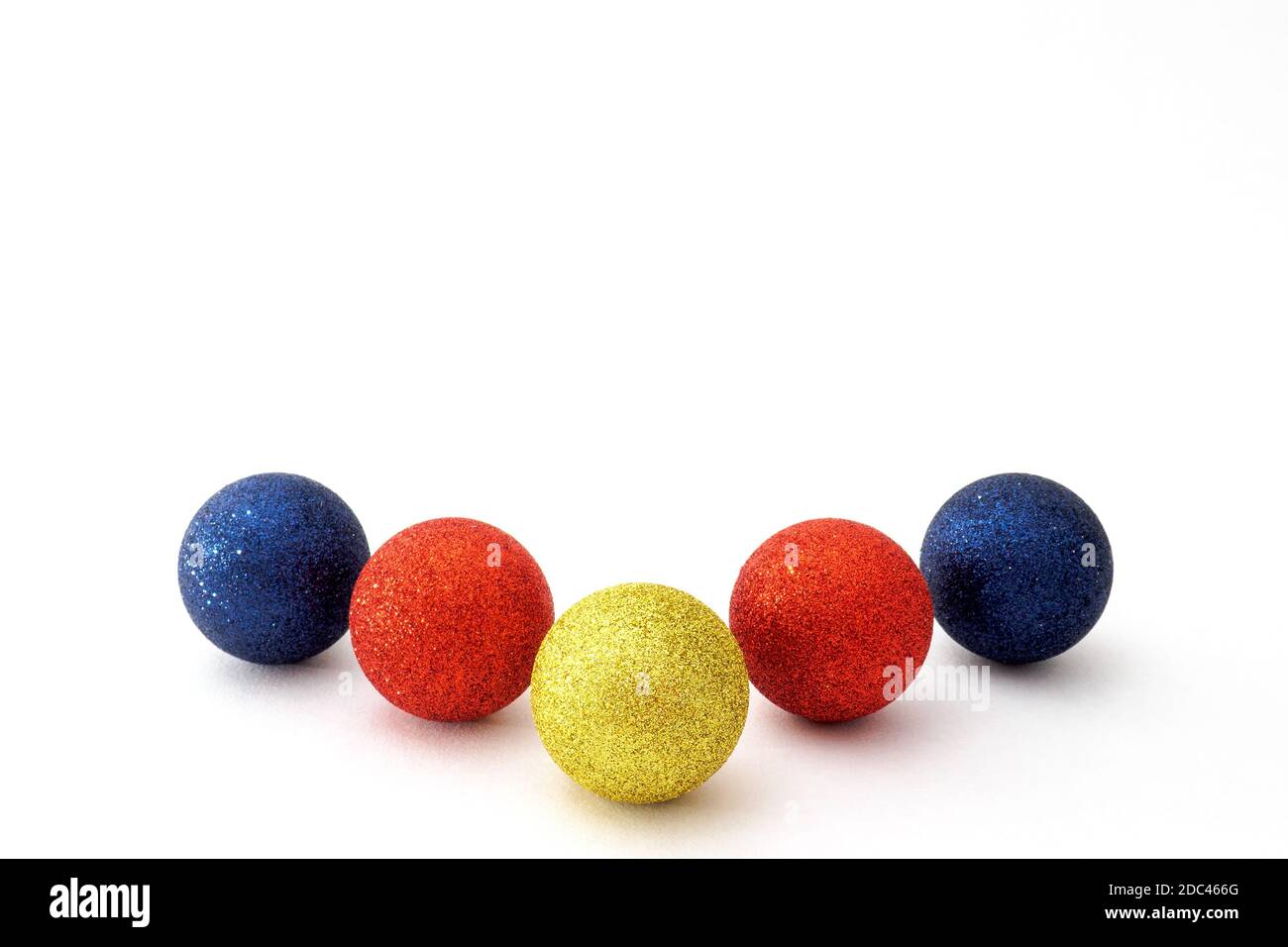 Five Christmas baubles blue, red and yellow color on white background. Selective focus, copy space Stock Photo