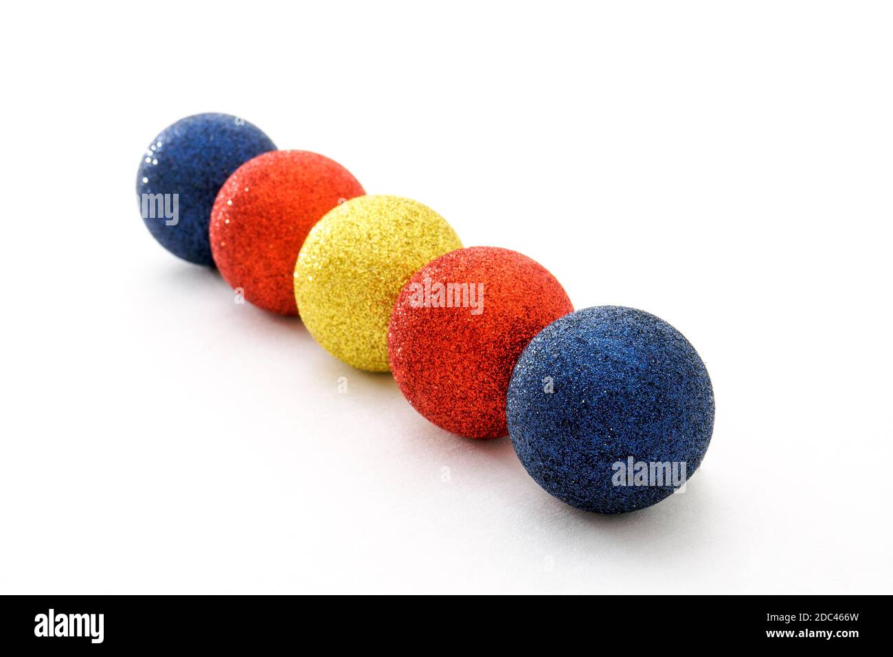 Five color Christmas baubles in row on white background. Selective focus Stock Photo