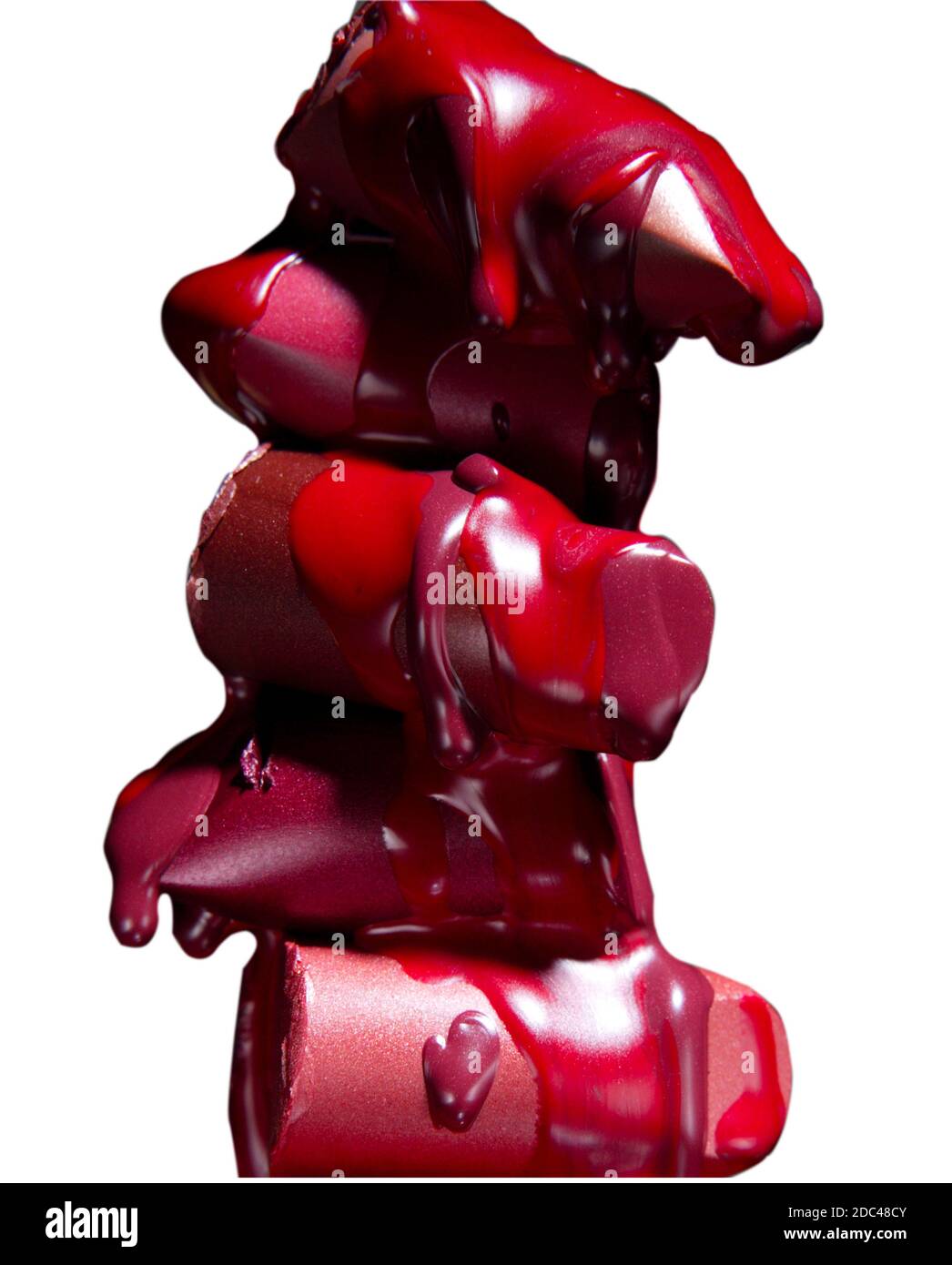 Stack of melting, dripping lipstick bullets.  Lipstick tops dripping in this dramatic, vertical, color studio photograph. Stock Photo