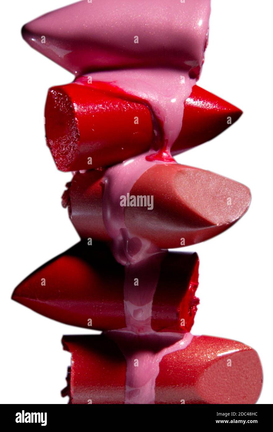 Stack of melting, dripping lipstick bullets.  Lipstick tops dripping in this dramatic, vertical, color studio photograph. Stock Photo