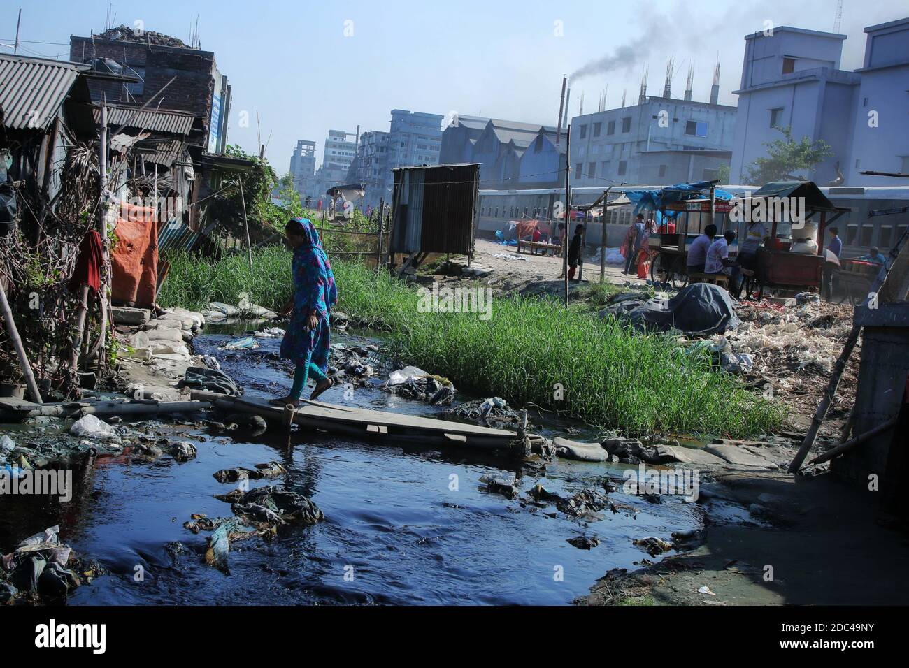 Dhaka, Bangladesh. 12th Nov, 2020. A woman seen using a wooden plank to enter her house as the road is flooded with the textile mills wastage at Shyampur industrial area in Dhaka.Most people in this area have become victims of pollution due to the presence of toxic chemicals, mainly dyeing chemical. Due to unplanned sewerage system of textile mills, residents of this area suffering for a long time. Credit: Sultan Mahmud Mukut/SOPA Images/ZUMA Wire/Alamy Live News Stock Photo