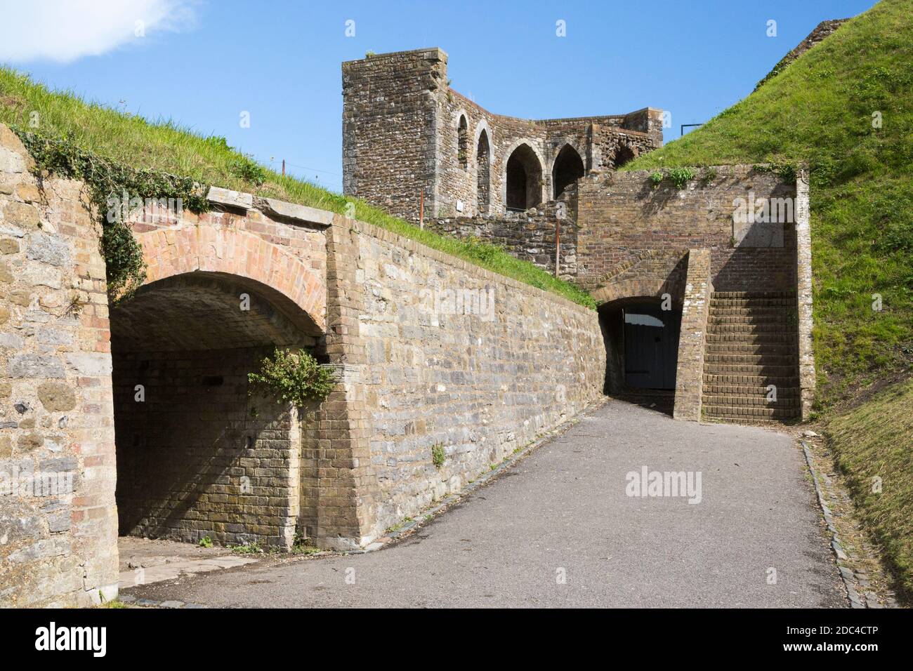 Defences, including tunnels built during the Napoleonic era, between the outer curtain wall (Left) and inner circuit walls of Dover Castle, Dover, Kent. UK. Avranches Tower is middle left against the blue sky. (121) Stock Photo