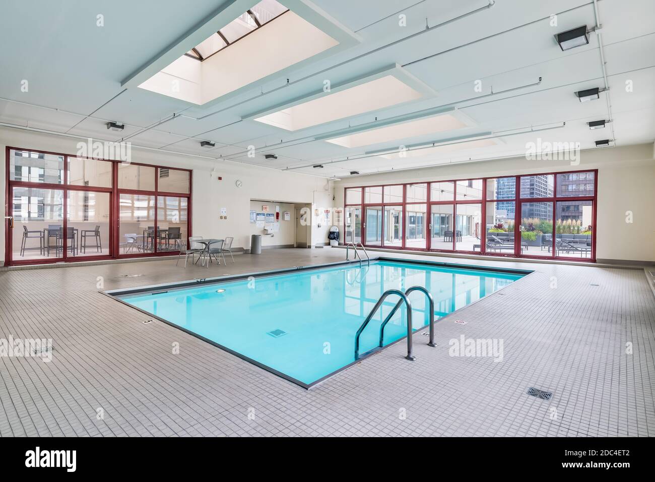 An indoor pool in a downtown Chicago high rise with seating and a door