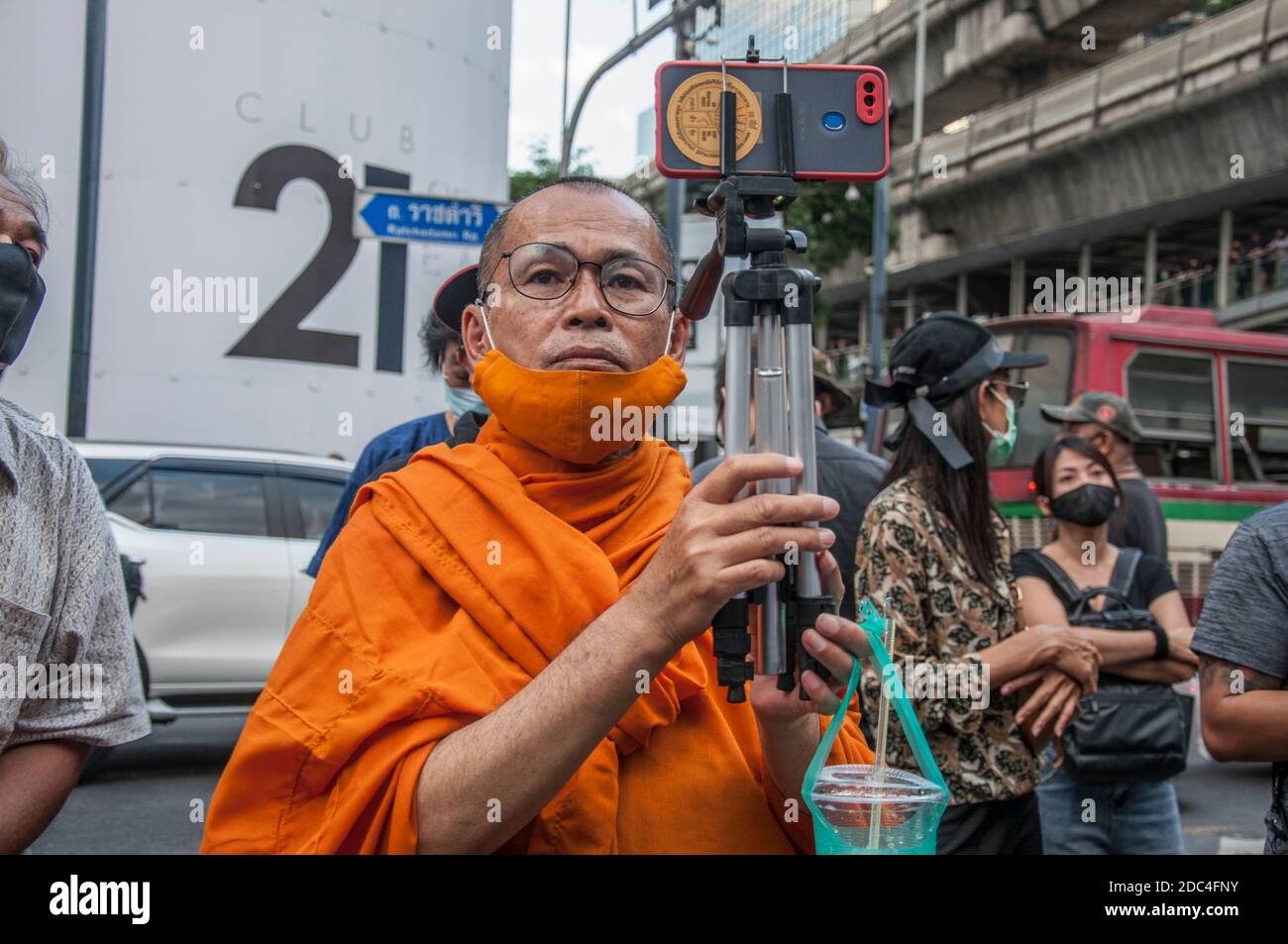 A monk live streaming with his mobile phone during the demonstration.Pro-democracy protesters gathered at Ratchaprasong intersection and marched towards the royal Thai police headquarter to splash colour and water following riot police using tear gas and high-pressure water cannons to prevent protesters from approaching Congress during the constitutional debate. Stock Photo