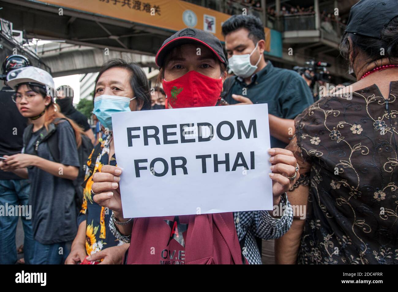 A protester holding a placard saying, freedom for Thai, during the demonstration.Pro-democracy protesters gathered at Ratchaprasong intersection and marched towards the royal Thai police headquarter to splash colour and water following riot police using tear gas and high-pressure water cannons to prevent protesters from approaching Congress during the constitutional debate. Stock Photo