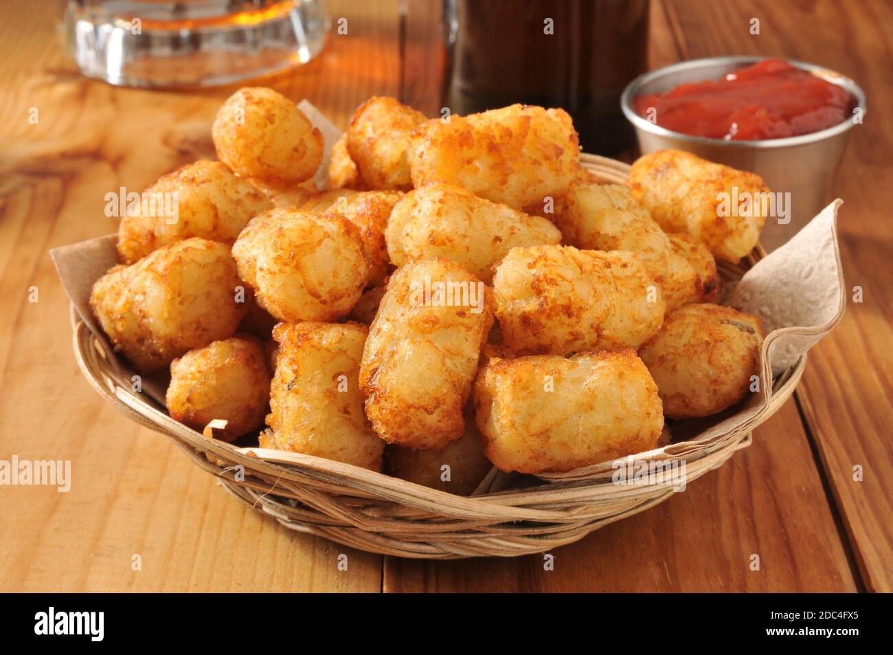 A basket of golden tater tots with beer in the background Stock Photo