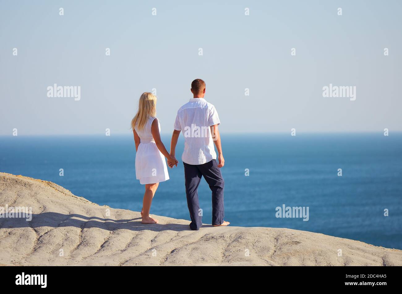 Young couple looking at the sea holding hands Stock Photo - Alamy