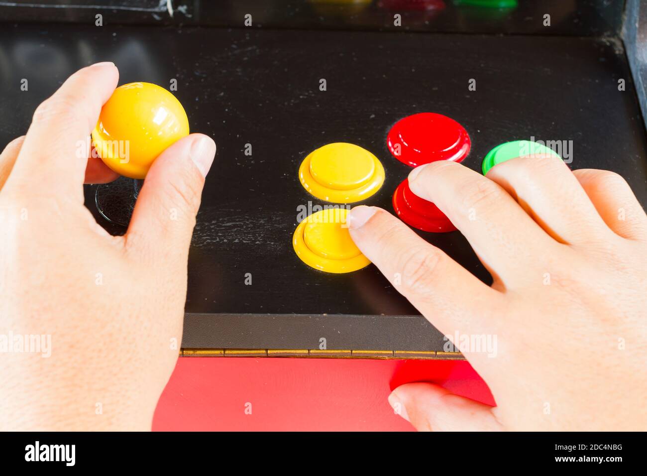 hands touching yellow joystick and buttons of old arcade video game