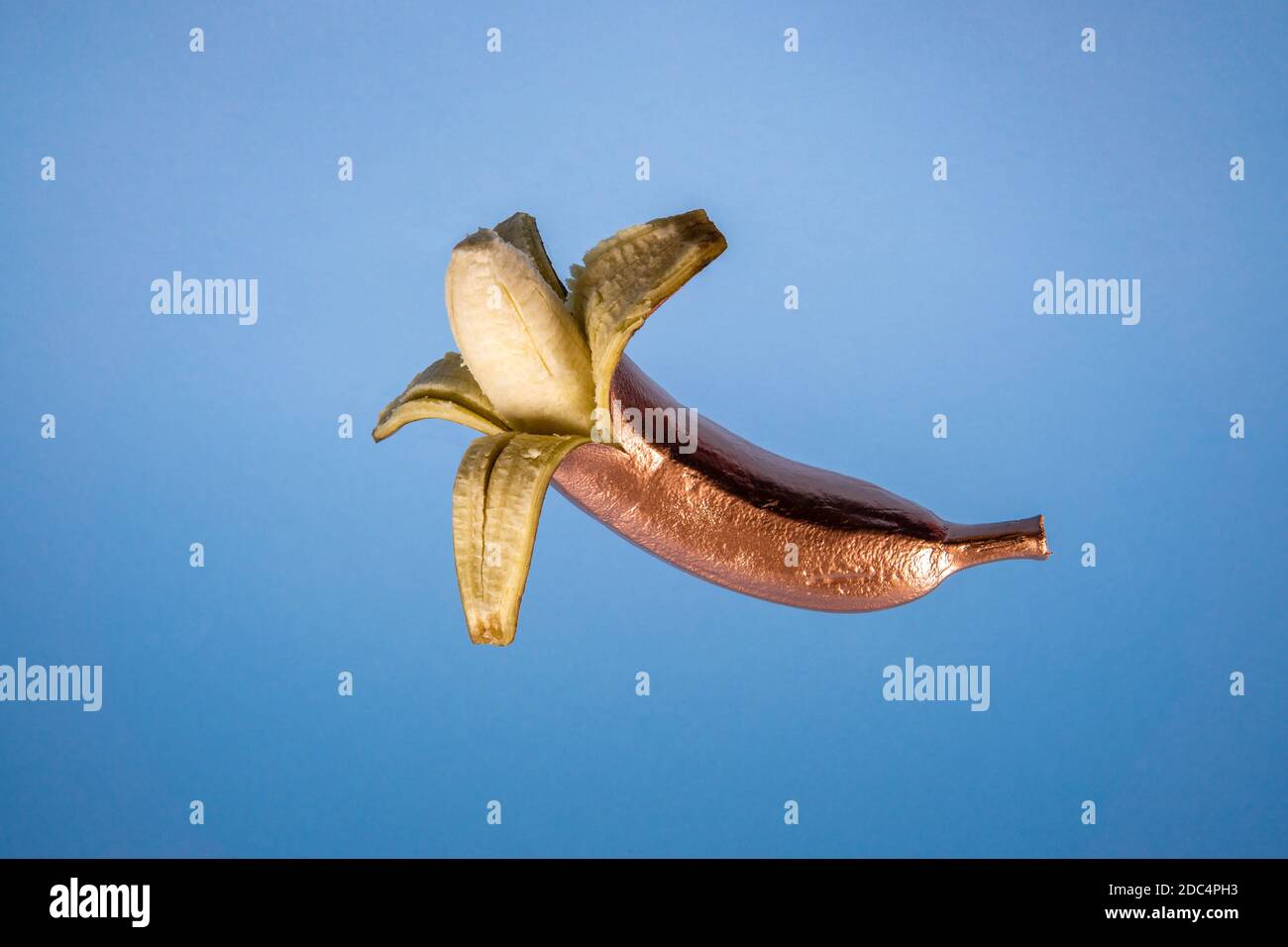 Gold floating pilled banana on blue background. Minimal food concept Stock Photo