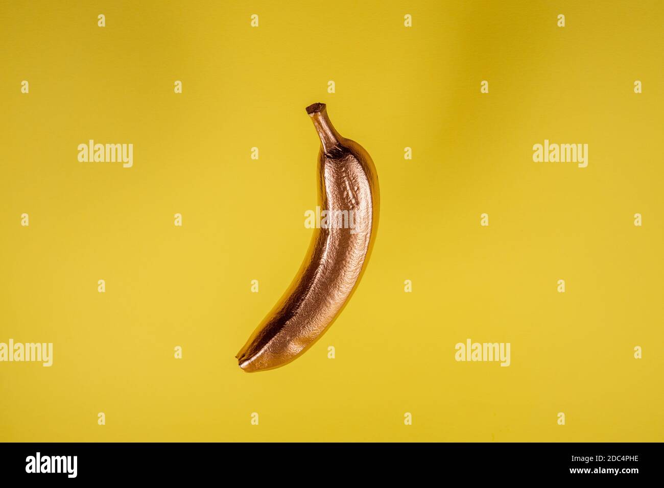 Copper gold floating banana on yellow background. Minimal food concept Stock Photo