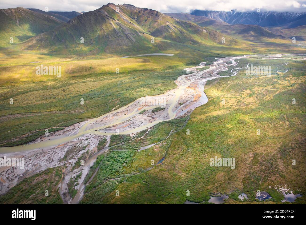 Aerial view of a glacial river valley and the Brooks Range at the Arctic National Wildlife Refuge in Northeastern Alaska. The remote Arctic National Wildlife Refuge covers approximately 19.64 million acres of land and is the largest wilderness in the United States. Stock Photo