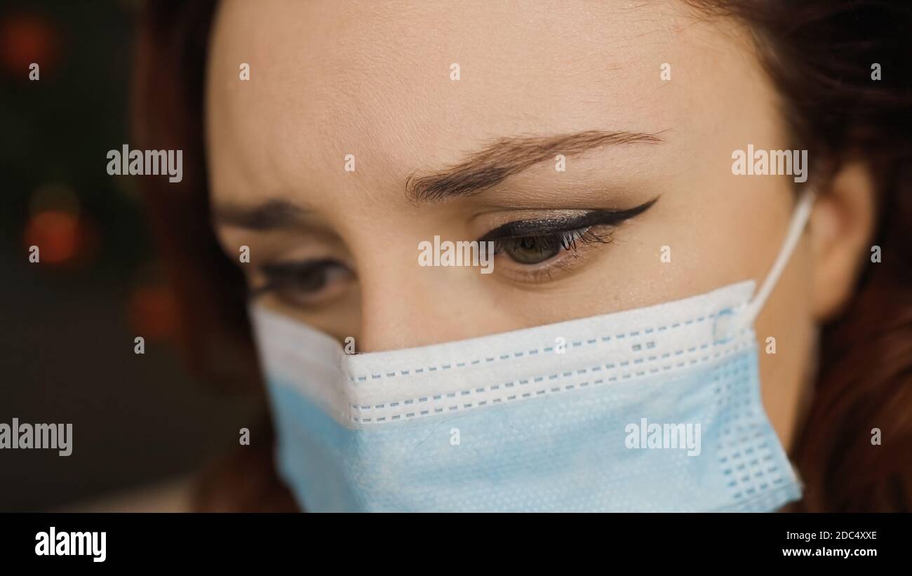 Macro eye view: Sad young woman in medical face mask looks away Stock ...