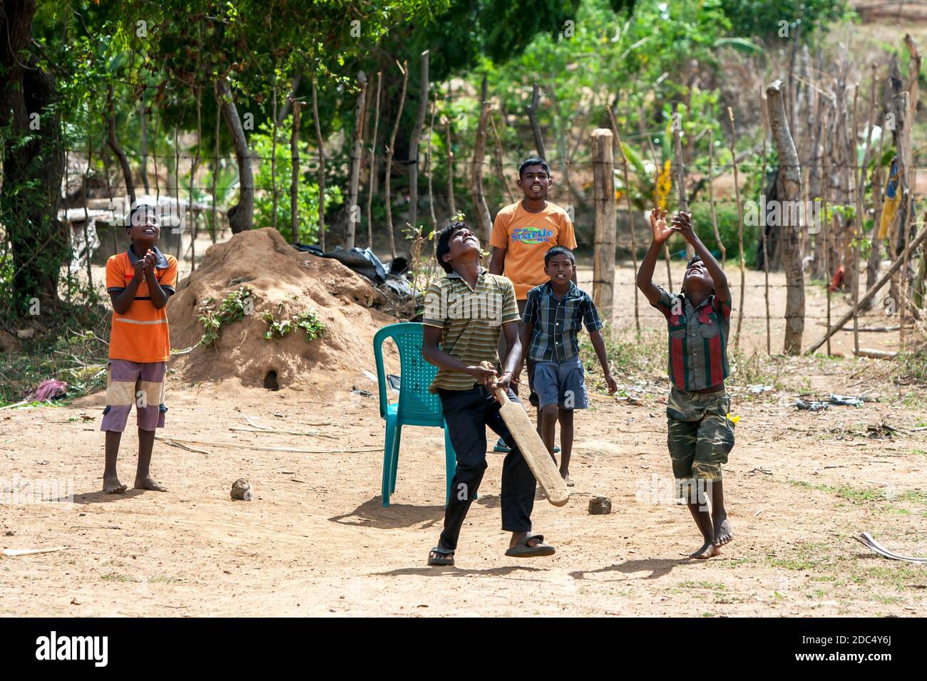 Sri Lankan boys play cricket on a dusty pitch near the town of Pottuvil on the east coast of Sri Lanka. Both batsman and fielder are watching the ball Stock Photo