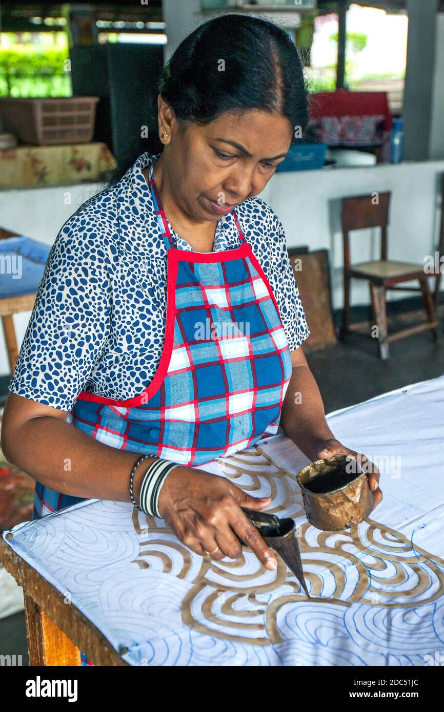 A worker applies wax to a batik using a canting tool prior to the