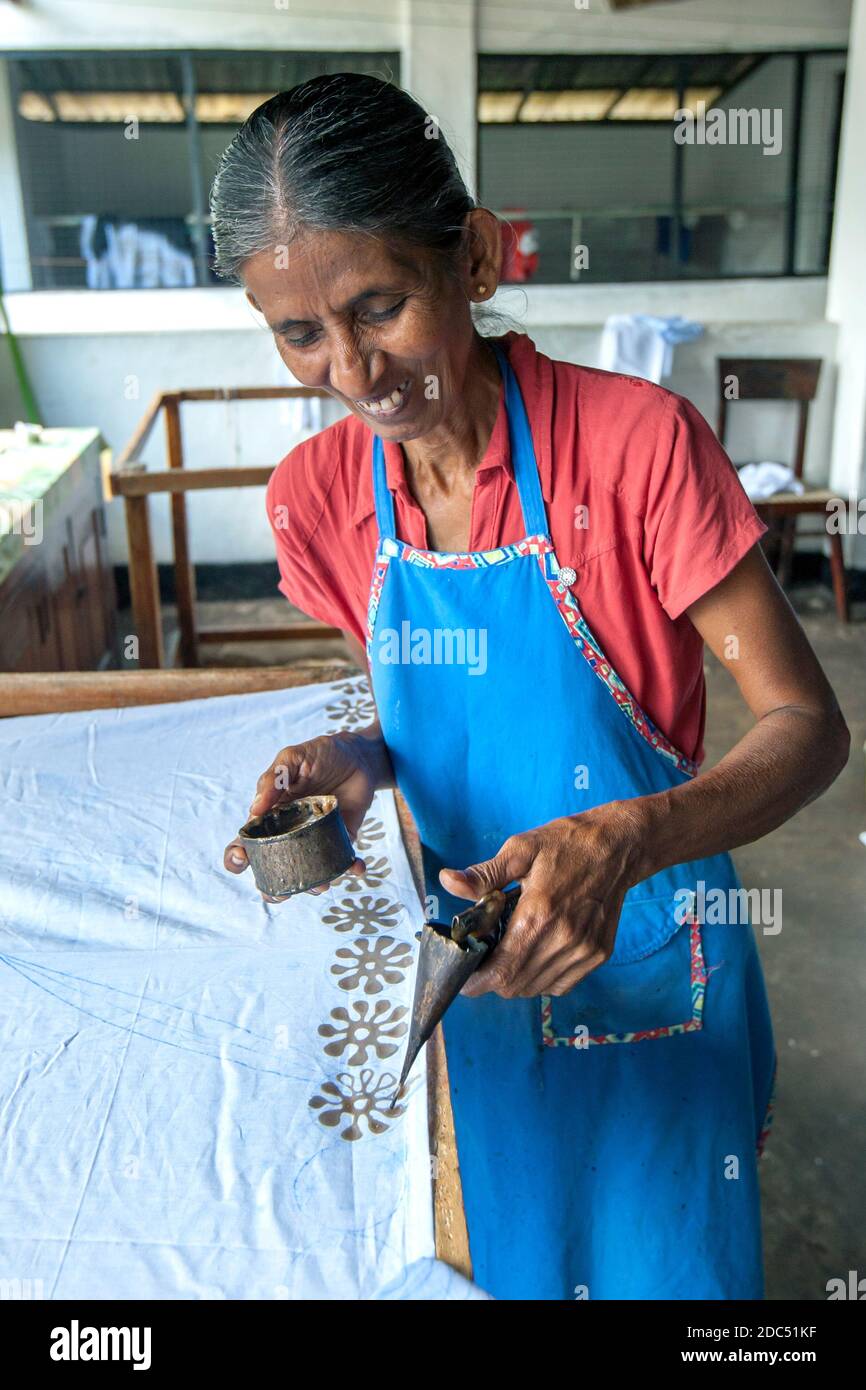 A worker applies wax to a batik using a canting tool prior to the