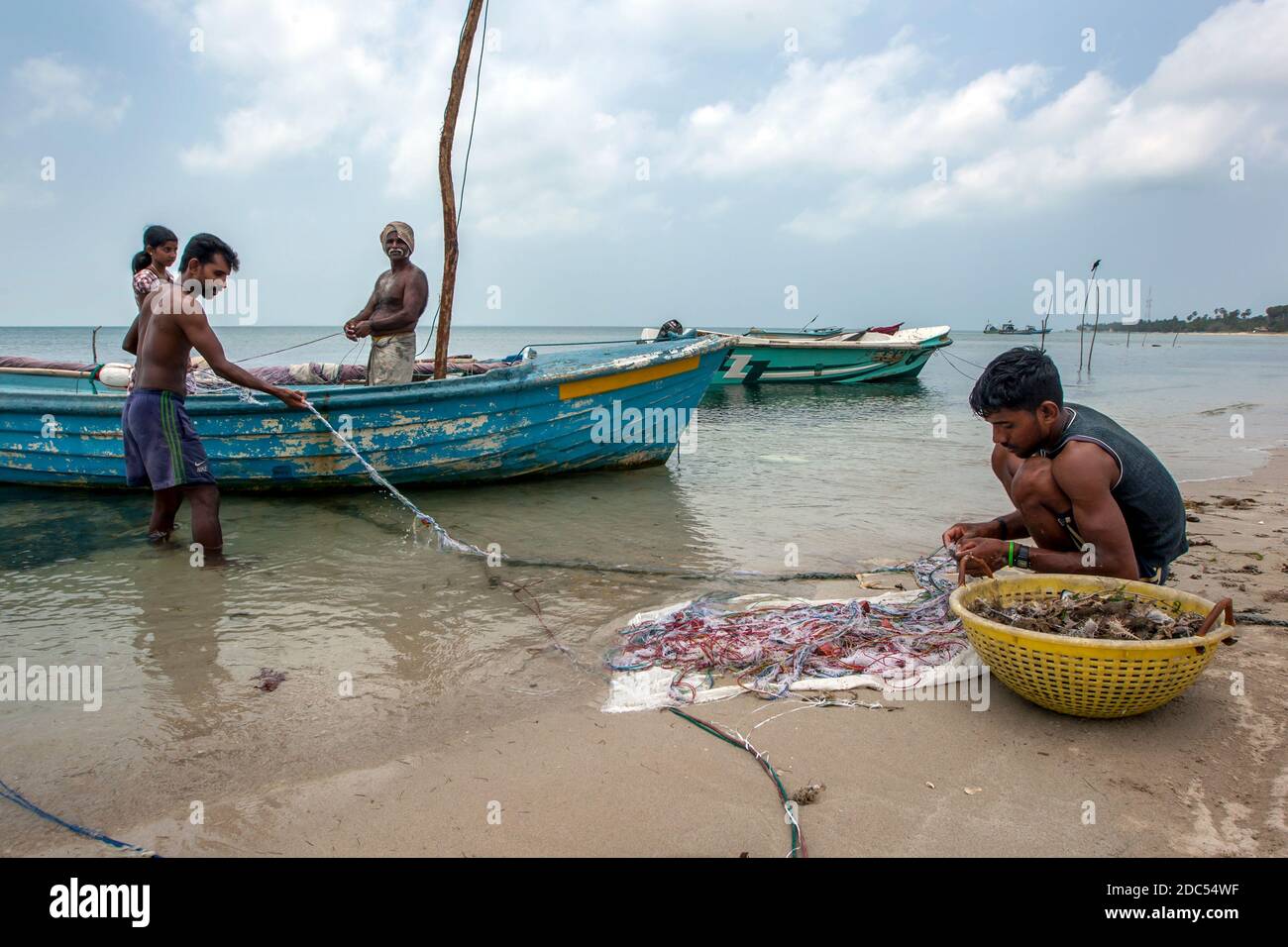 Fishermen and women attending to their nets on a west coast beach on Delft Island in the Jaffna region of Sri Lanka. Stock Photo