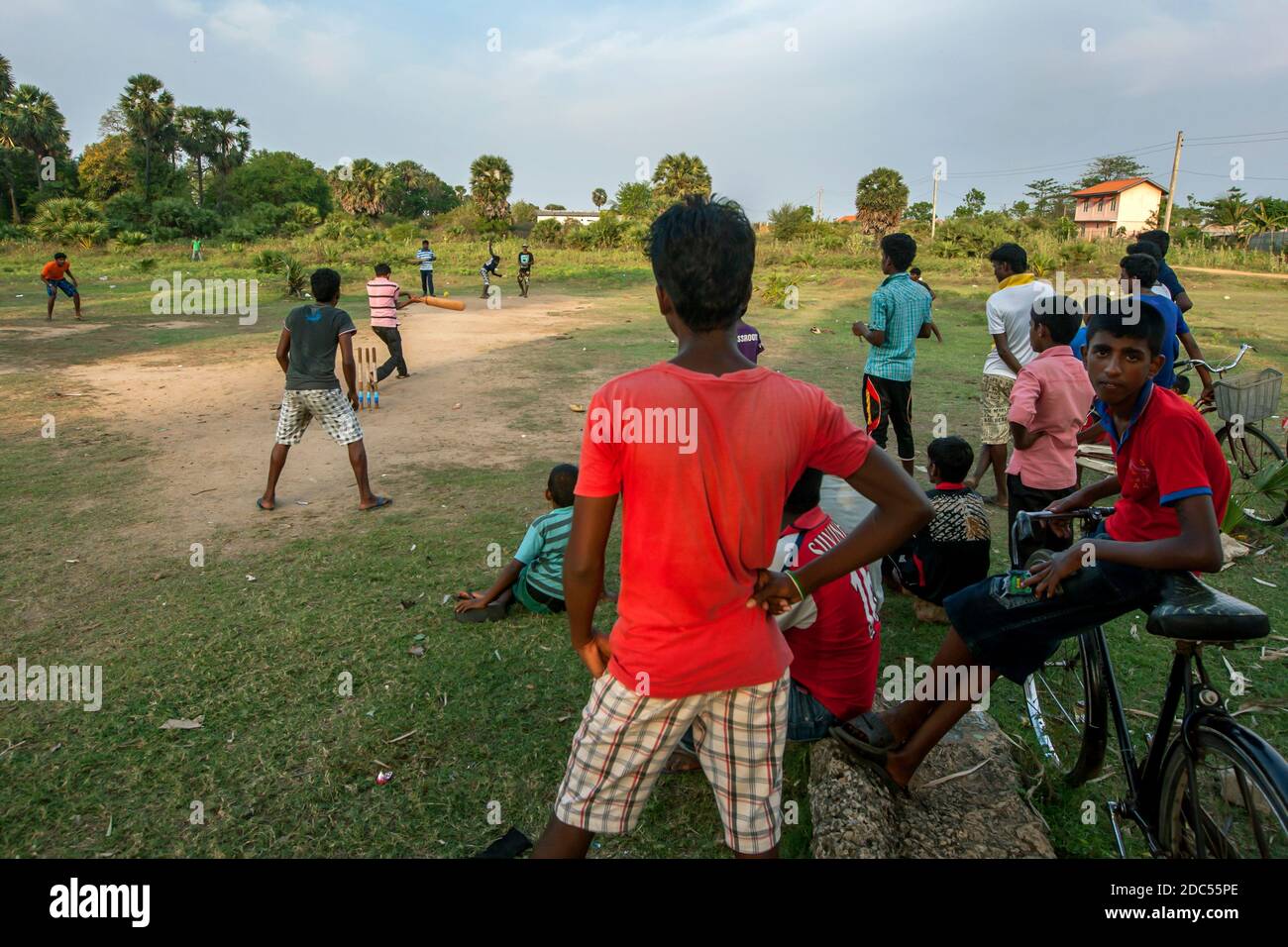 Spectators watch a cricket game being played on a dirt pitch on a Sunday afternoon in Uppuveli on the east coast of Sri Lanka. Stock Photo
