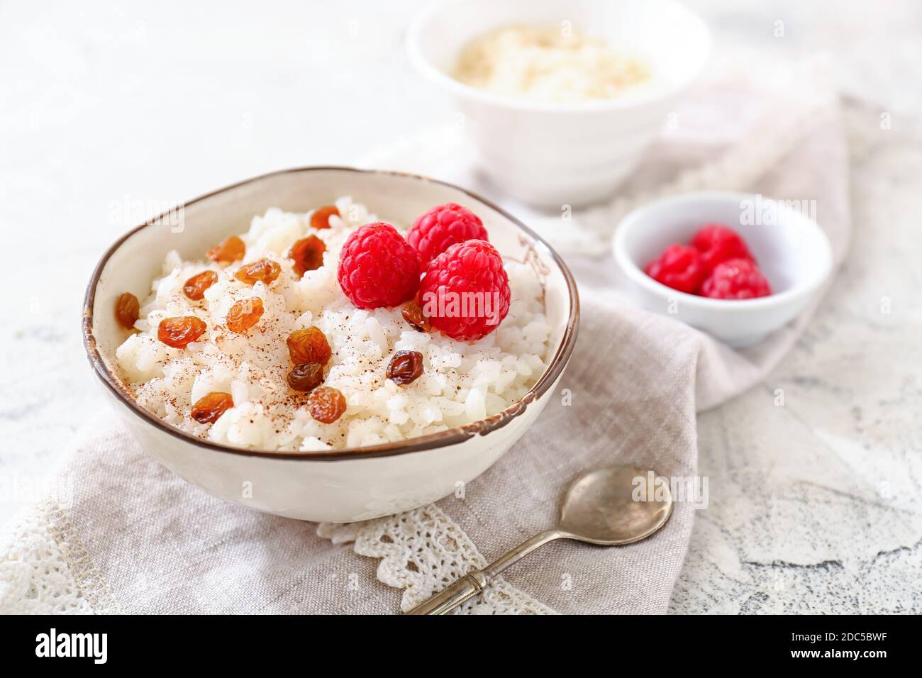 Raspberry Raisins Bowl of tasty rice pudding with raspberry and raisins on light table ...
