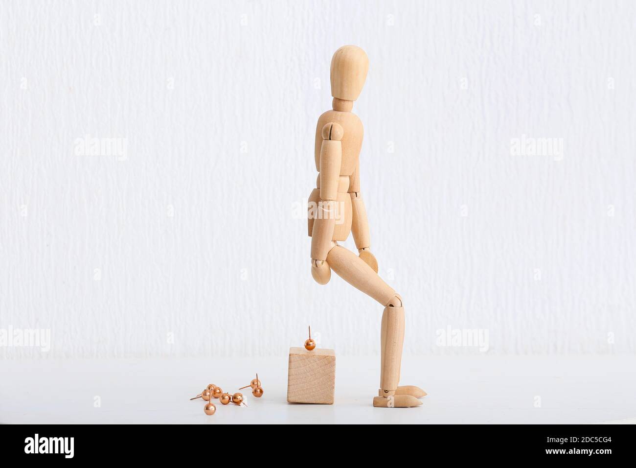 Wooden mannequin and pins on white background. Concept of hemorrhoids Stock Photo