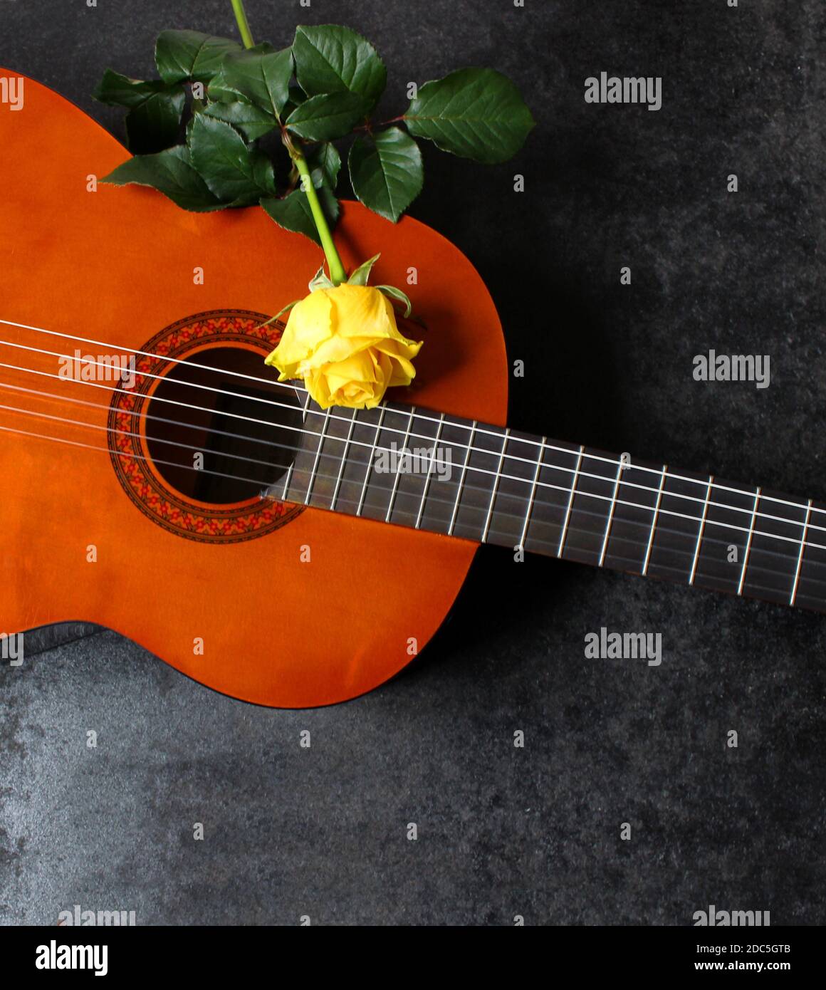 Light acoustic guitar and yellow rose. Beautiful romantic background. Stock Photo