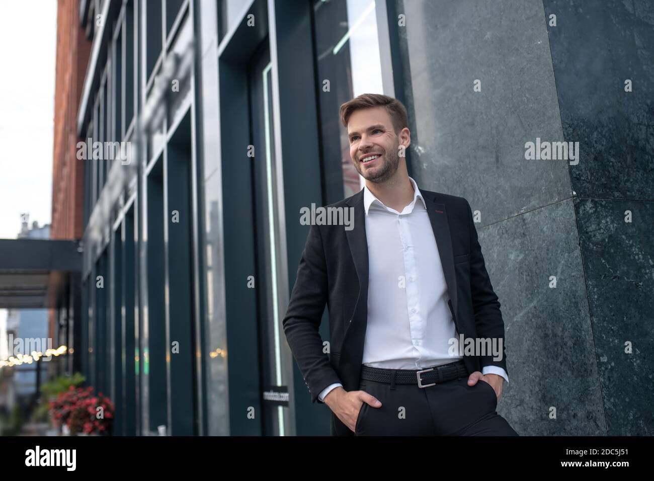 Elegant young man in a black suit smiling and feeling good Stock Photo ...