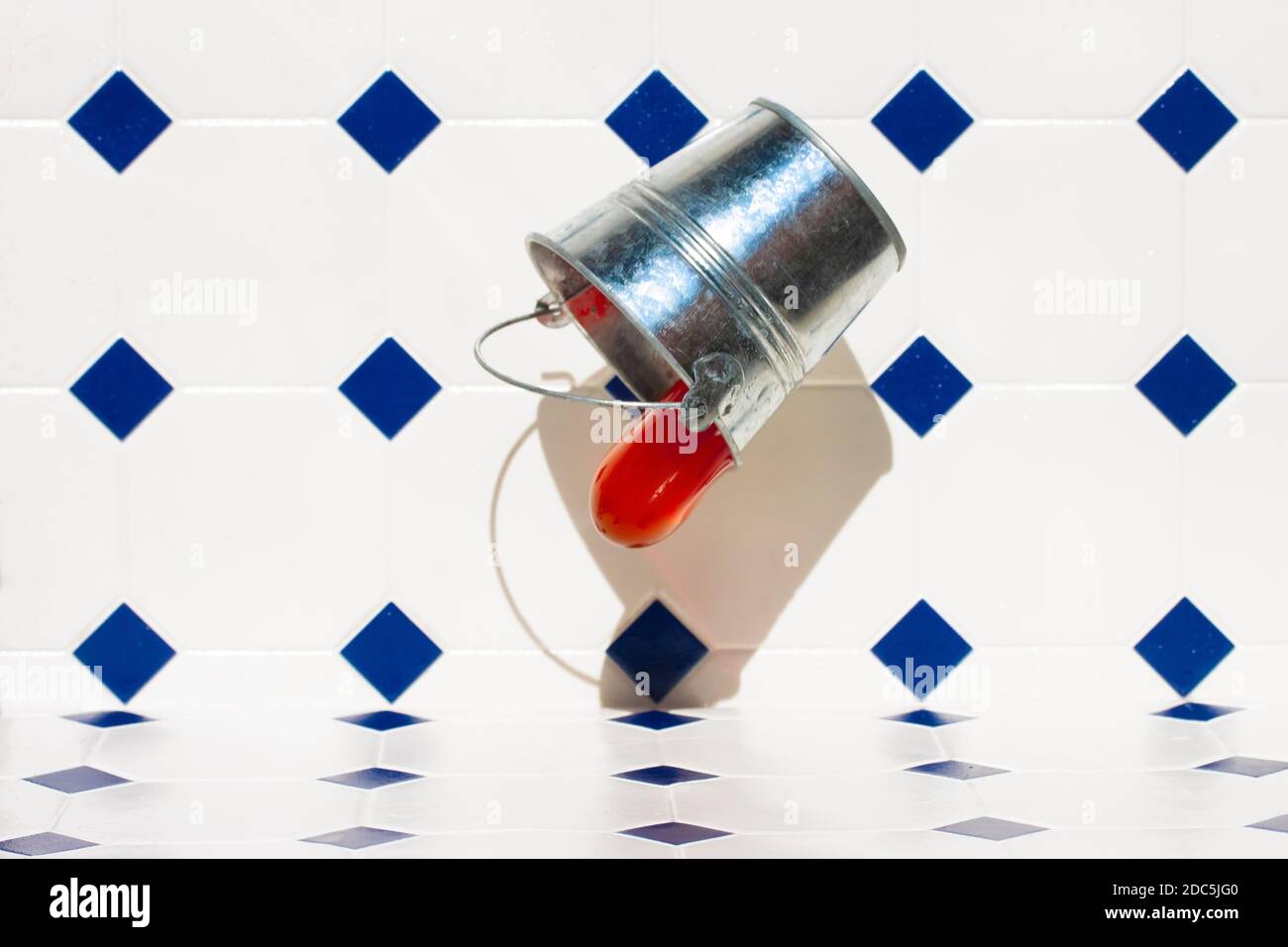 A tin bucket falling to the floor and a red liquid flows from it Stock ...