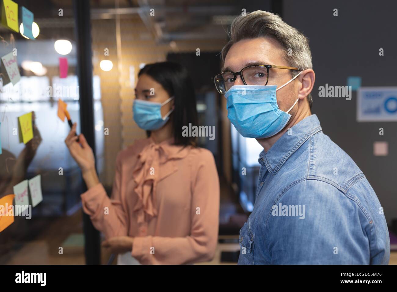 Portrait of caucasian man wearing face mask standing in modern office Stock Photo