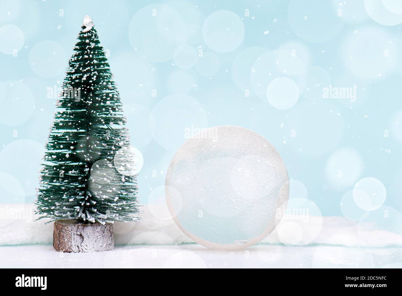 Christmas or New Year composition, decoration with glass ball snow globe and fir tree covered by snow on glitter background Stock Photo