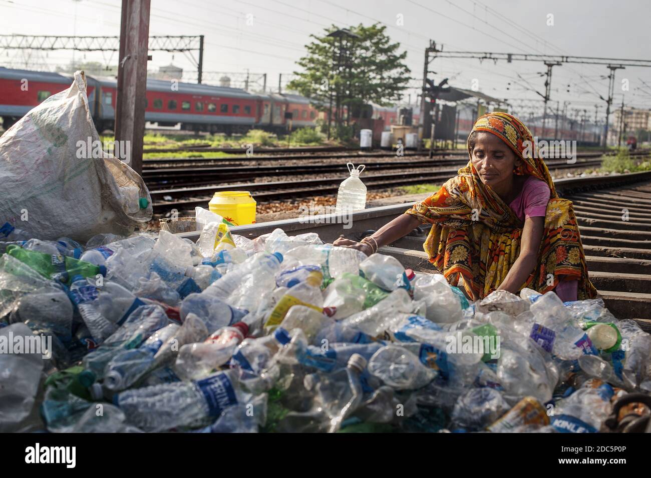 A woman belonging to the caste of the untouchables (Dalit) selects bottles and other plastic containers collected in the streets of Kolkata to sell. Stock Photo