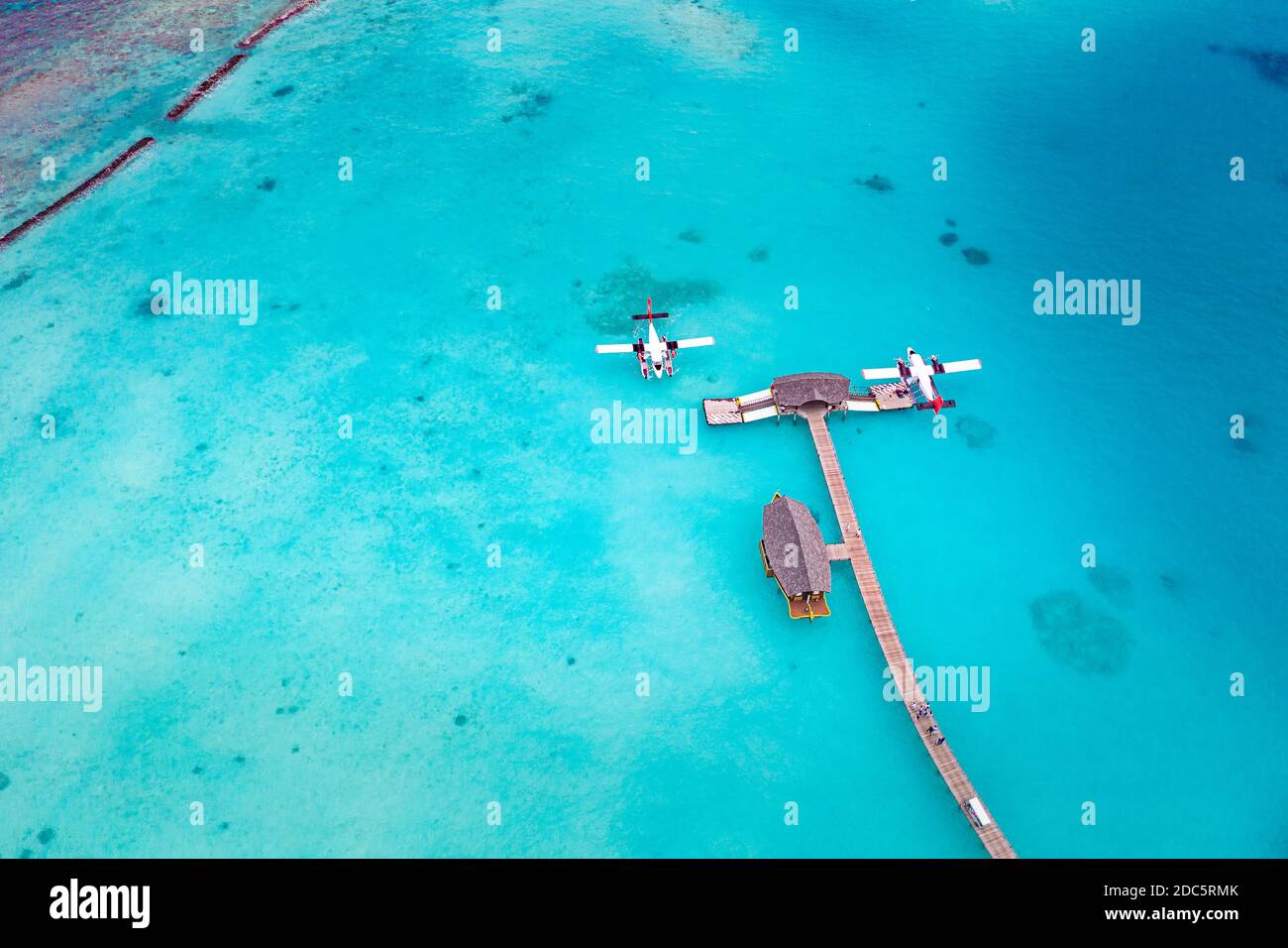 Beautiful aerial view of Maldives jetty seaplane top view with wooden boat Dhoni and tropical beach, jetty over wonderful blue sea. Luxury travel Stock Photo
