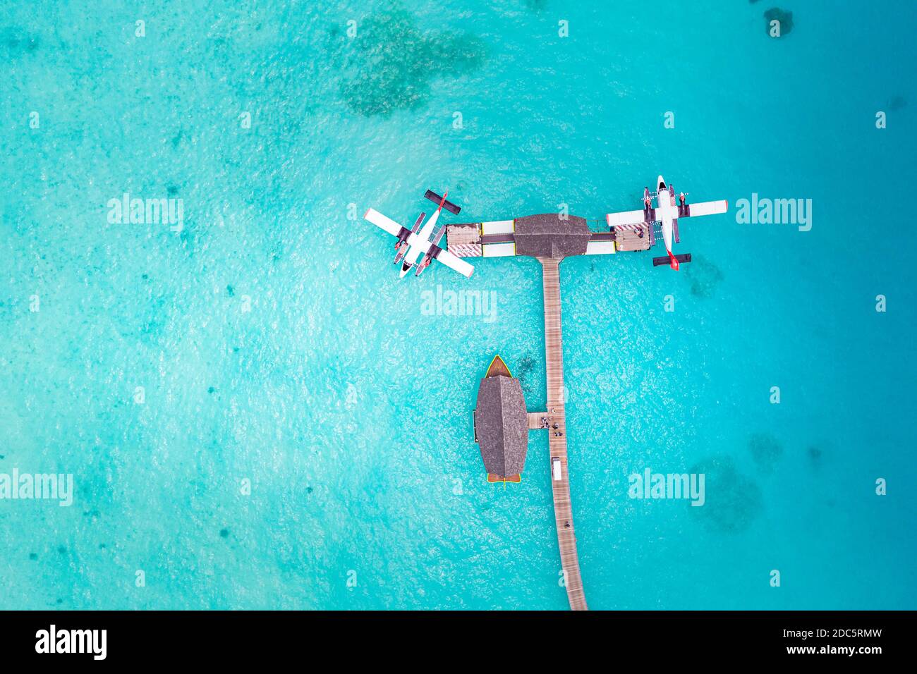 Beautiful aerial view of Maldives jetty seaplane top view with wooden boat Dhoni and tropical beach, jetty over wonderful blue sea. Luxury travel Stock Photo