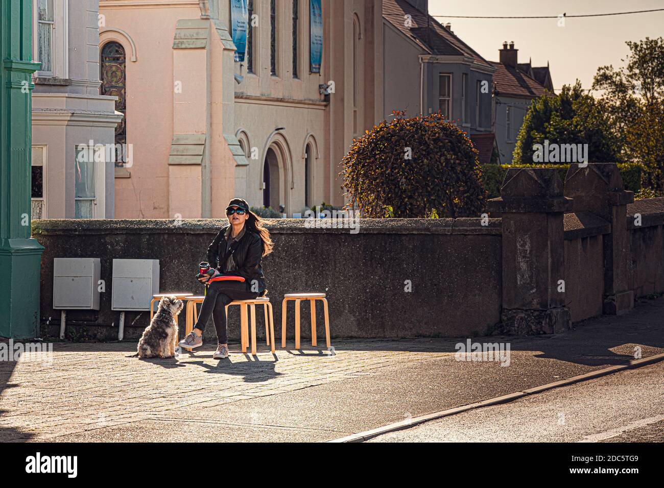 Everyday Life. Lady with dog have cup of coffee outside of the pub at sunny day. Stock Photo