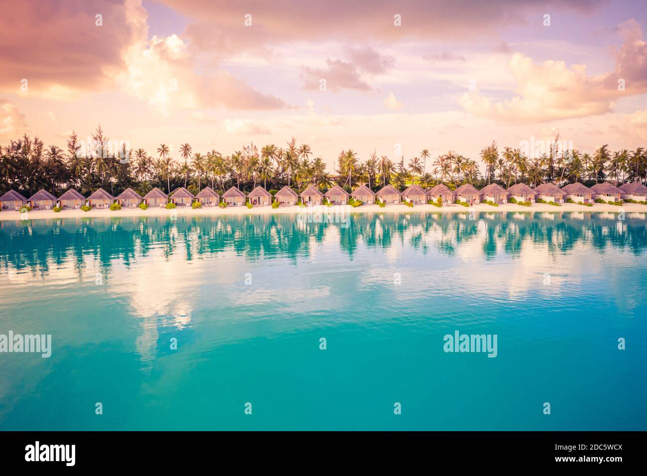 Beautiful colorful sunset at tropical island on Maldives in Indian Ocean. Luxury beach villas with palm trees. Amazing summer destination scenic relax Stock Photo