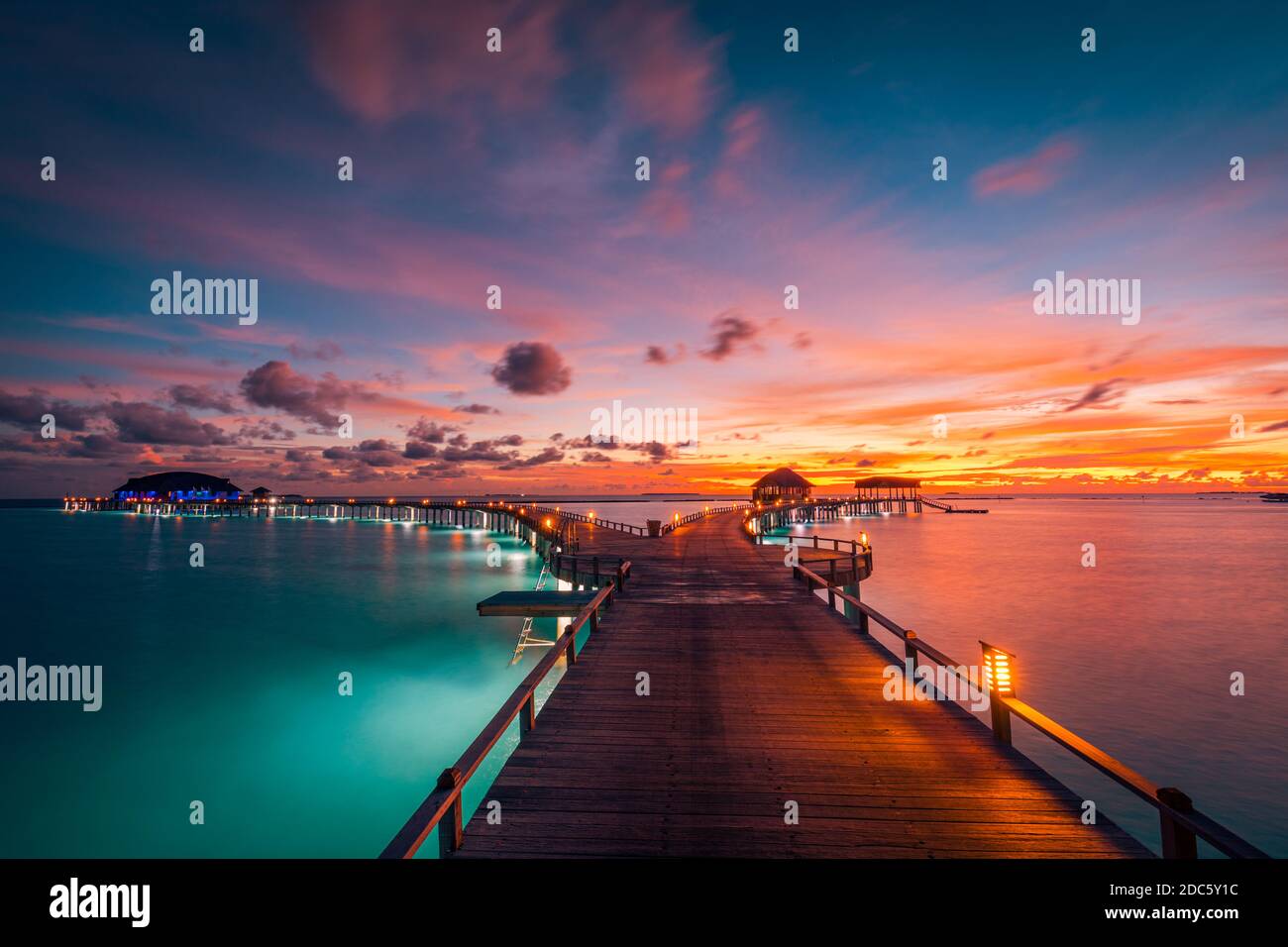 Nature sunset on Maldives island, luxury water villas resort and wooden pier. Beautiful sky clouds and beach nature background for summer vacation Stock Photo