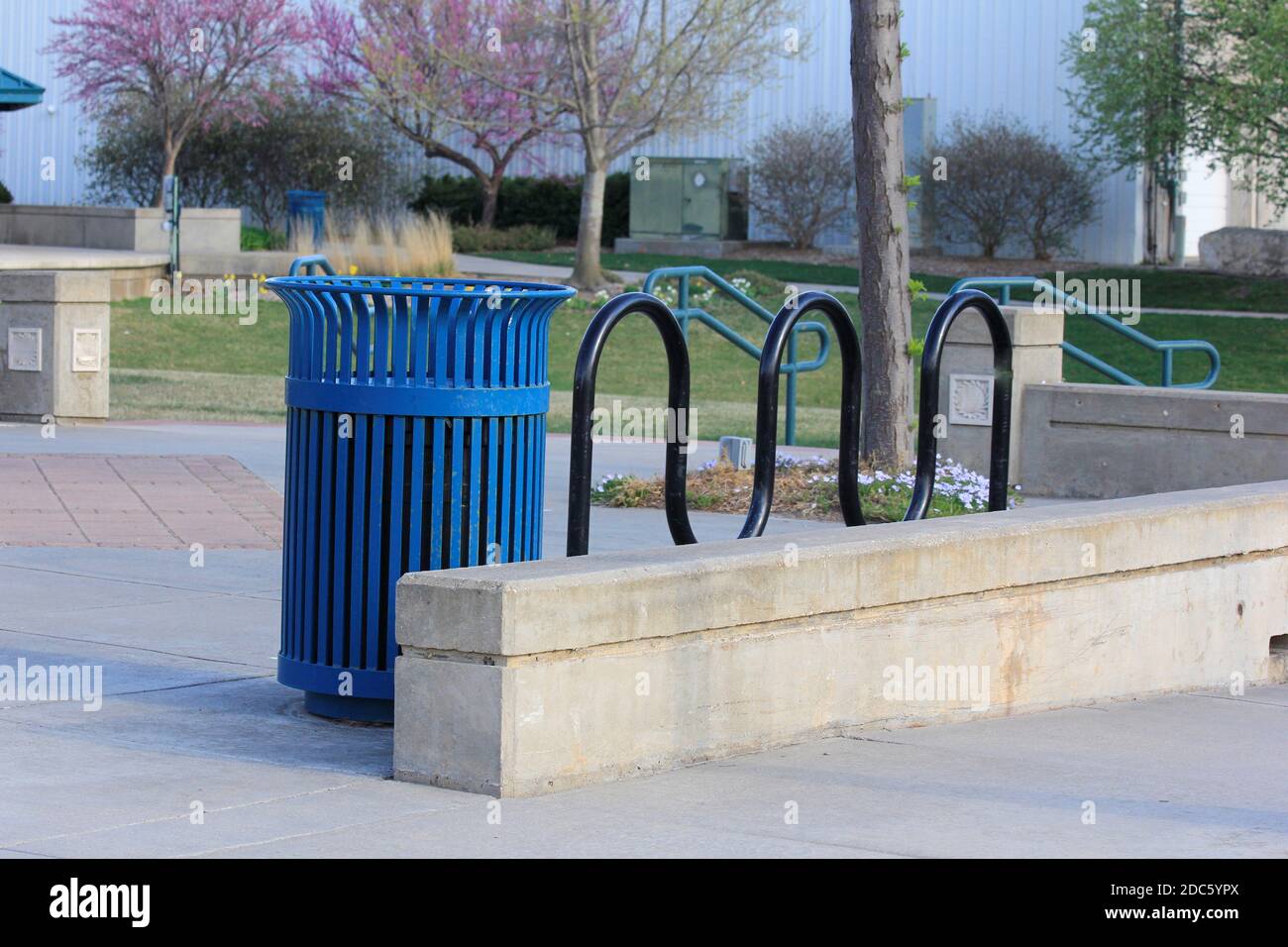 Hutchinson Kansas city park with green grass, tree's, trash can and cement side walk on a spring day. Stock Photo