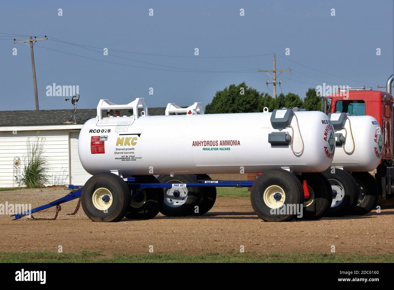 Anhydrous Ammonia Tanks in a farm yard with a truck and a building with blue sky in Kansas. Stock Photo