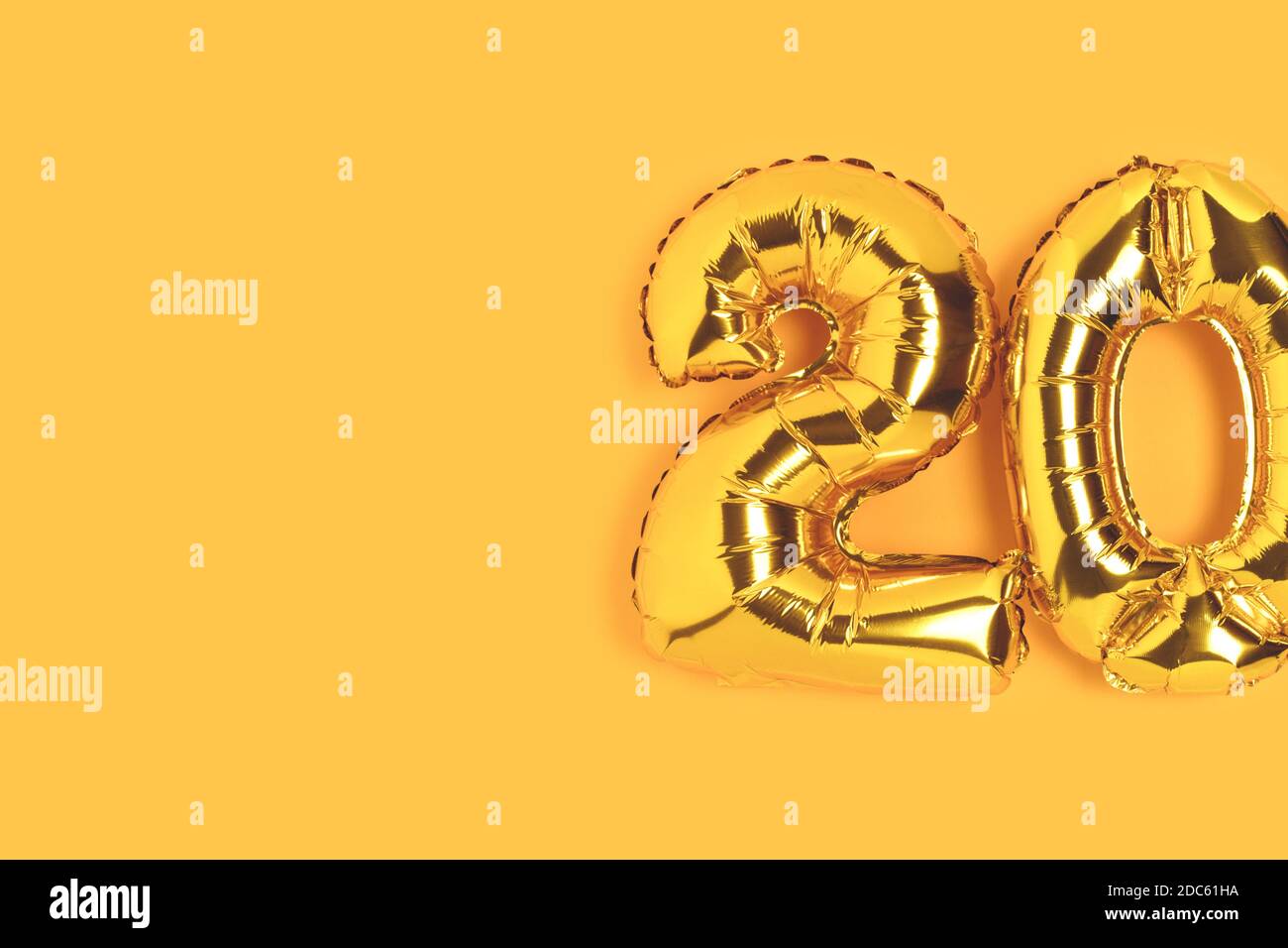 Number 20 golden balloons with copy space. Twenty years anniversary celebration minimalist concept on a yellow background. Stock Photo