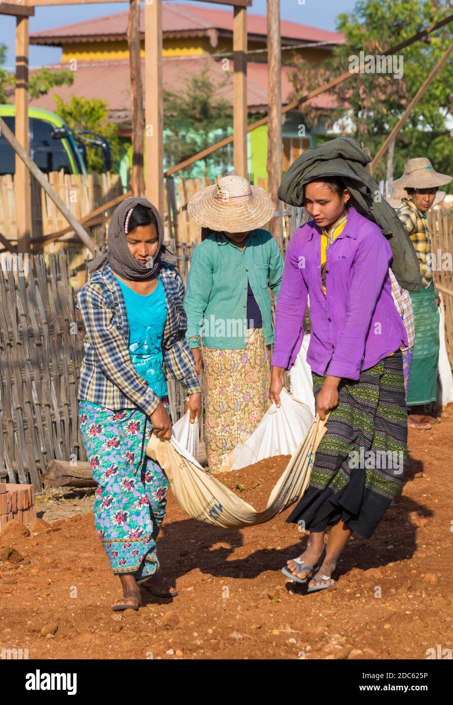 Villagers undertake manual road construction work at West Phwar Saw Village, Bagan, Myanmar (Burma), Asia in February - women moving materials Stock Photo