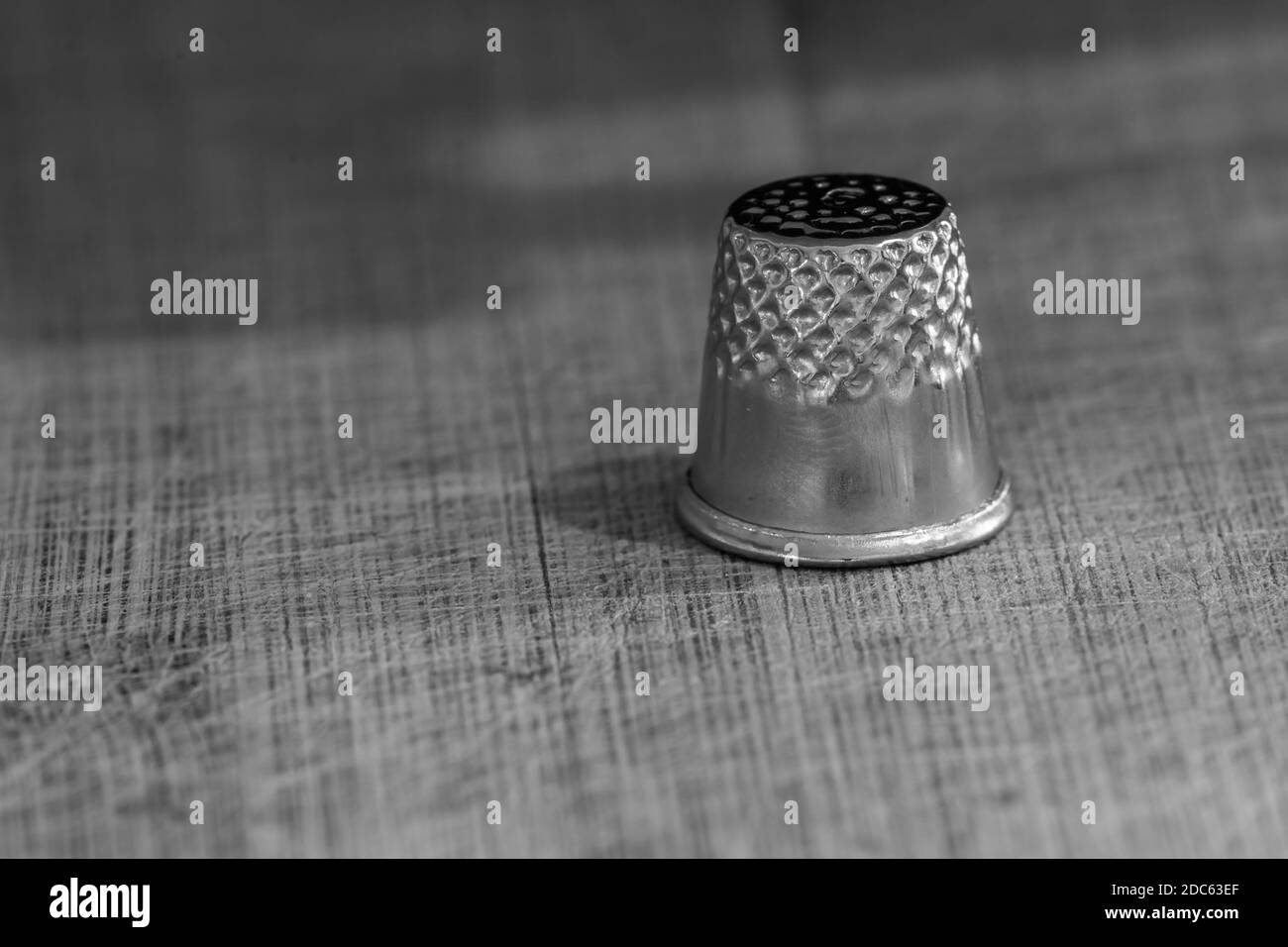 A grayscale shot of thimble on wooden background Stock Photo