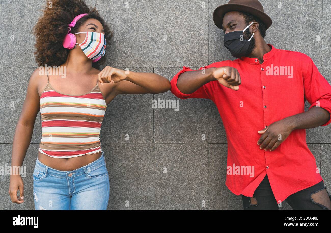 African friends wearing face protective mask while doing new social distance greetings bumping elbows Stock Photo