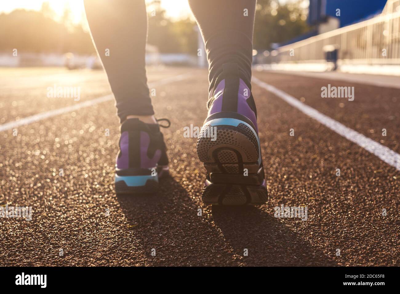 Runner feet running on stadium tracks closeup on shoe. Woman fitness