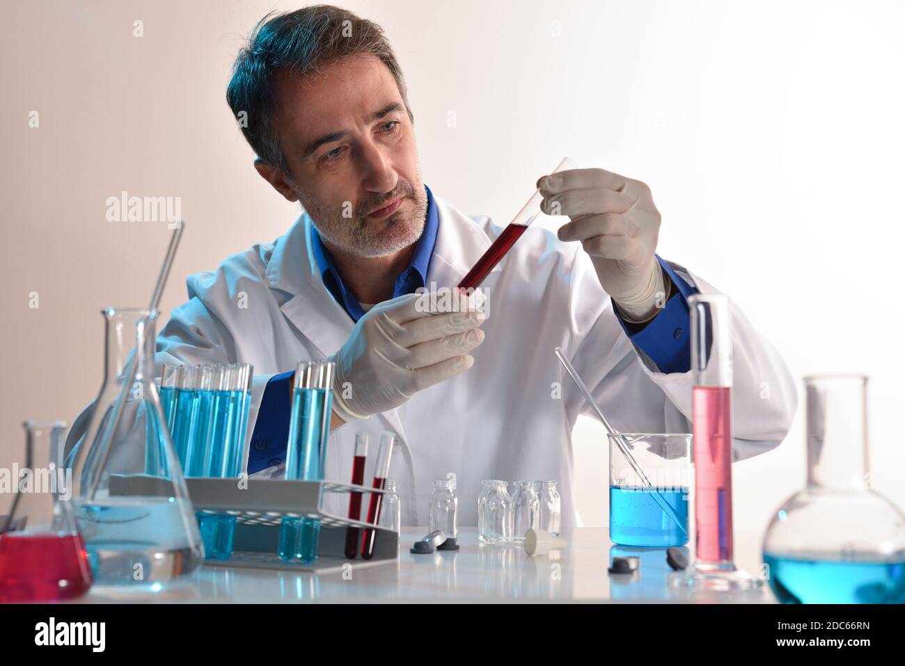 Researcher in laboratory looking at a sample in a test tube. Horizontal