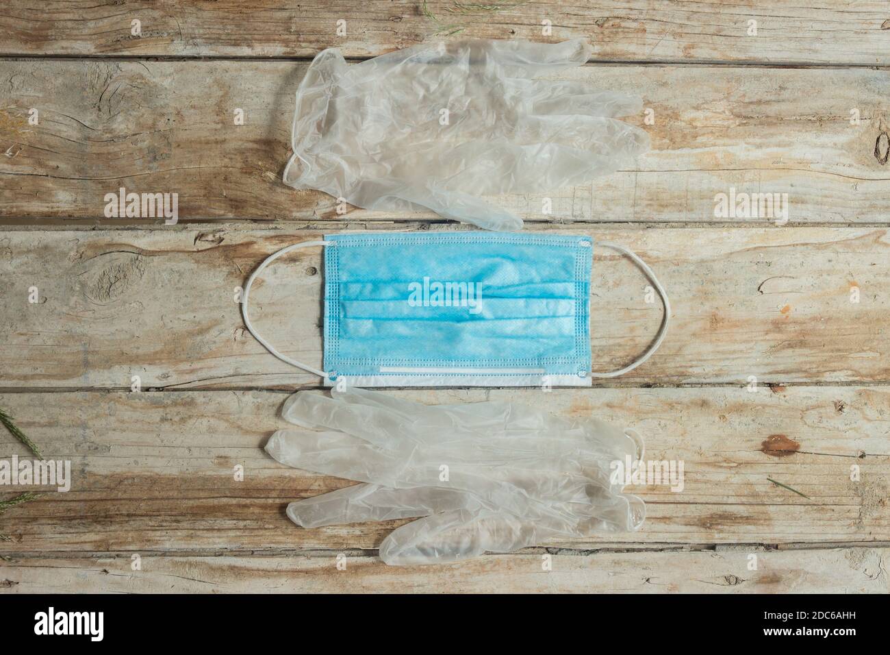 Two transparent plastic gloves and a surgical mask on a wooden table in the interior of a studio. Stock Photo