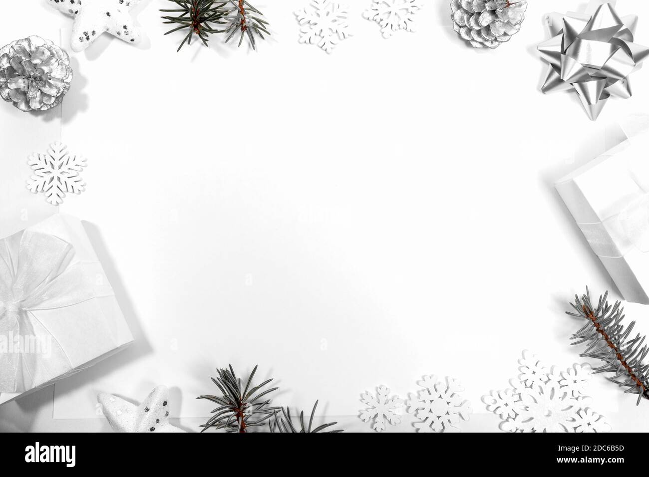 Frame made of white and silver Xmas Decorations: stars, DIY gift boxes, pine cones, snowflakes, fir branches on white. Christmas modern nordic layout. Stock Photo