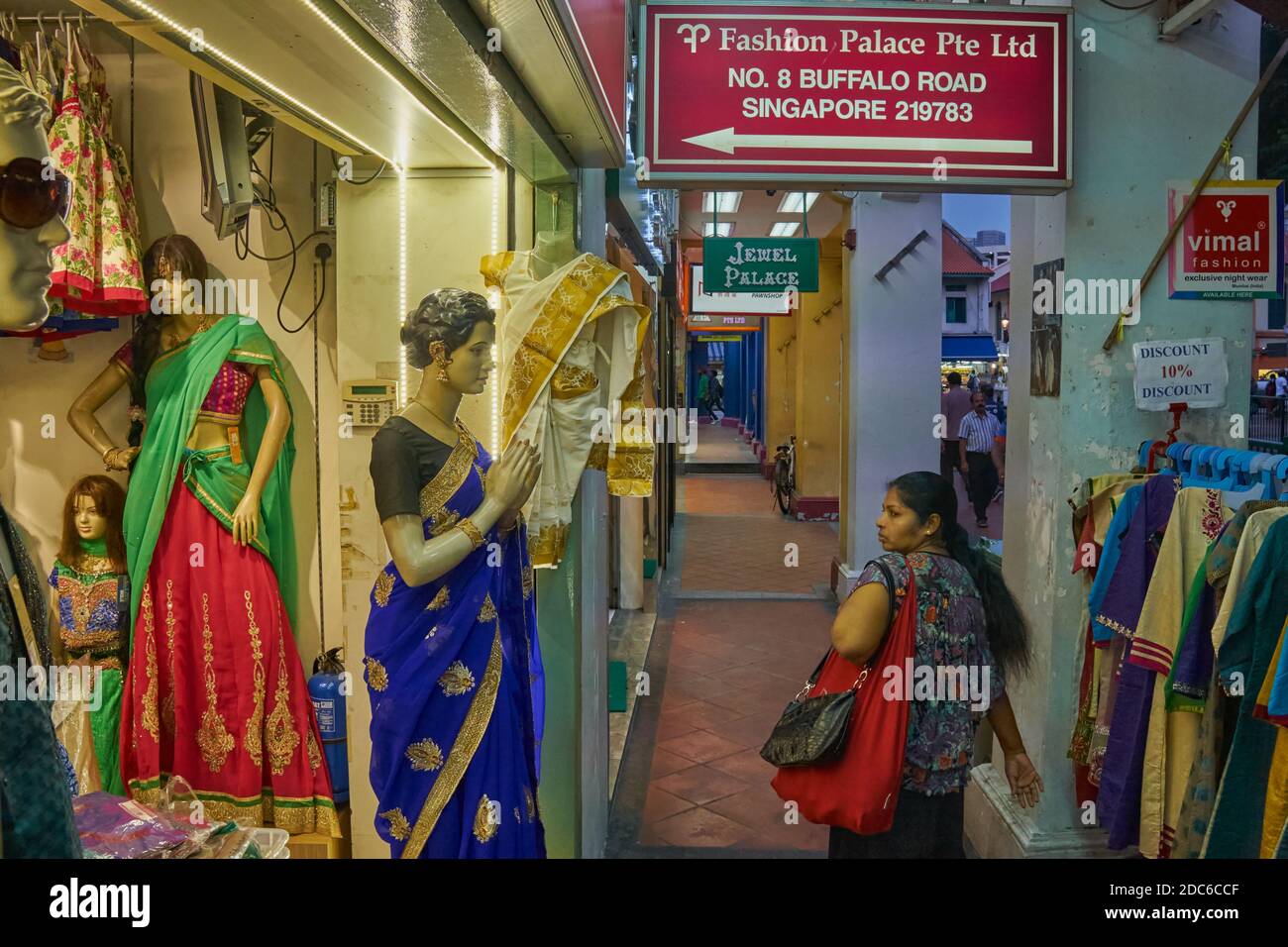 An ethnic Indian woman in Buffalo Road, Little India, Singapore, passing a shop windows with a display of traditional Indian female dress Stock Photo