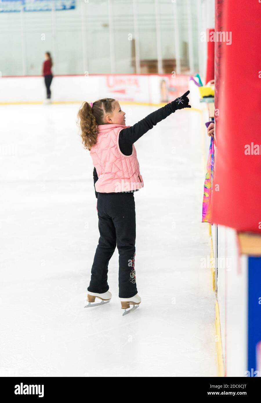 Little girl practicing figure skating elements on indoor ice skating